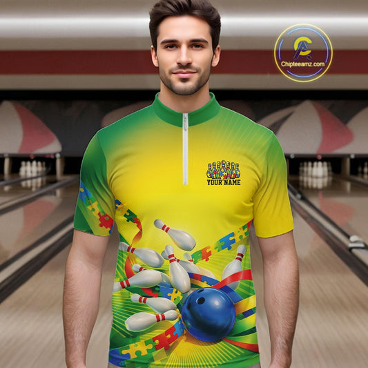 Male model in a bowling lane wearing a green and yellow quarter-zip shirt, autism puzzle bowling ball and pins with vibrant colorful illustration.