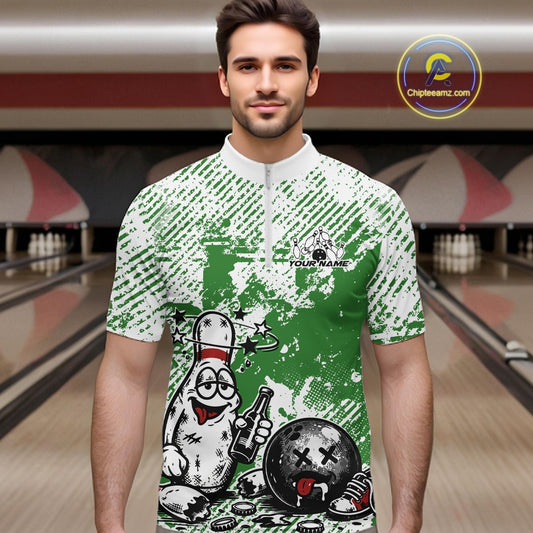 Male model in a bowling lane wearing a green and white quarter-zip shirt, funny drunk bowling pin illustration holding beer bottle and bowling ball.
