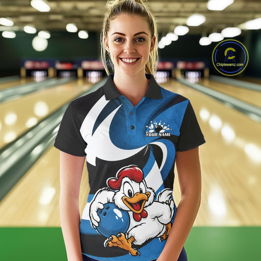 A woman stands in a bowling alley wearing a custom printed polo shirt. The shirt features a black and blue design with a large cartoon rooster holding a blue bowling ball, and the text 'YOUR NAME' on the chest.