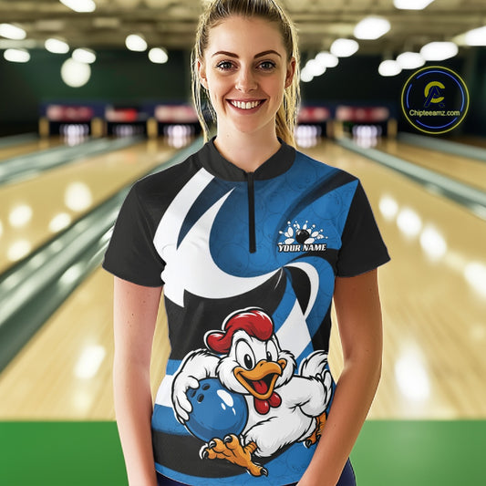 A woman wearing a custom bowling-themed short-sleeve quarter zip shirt with a blue, black, and white graphic design featuring a cartoon chicken holding a bowling ball. The background shows a blurred bowling alley with lanes and pins.