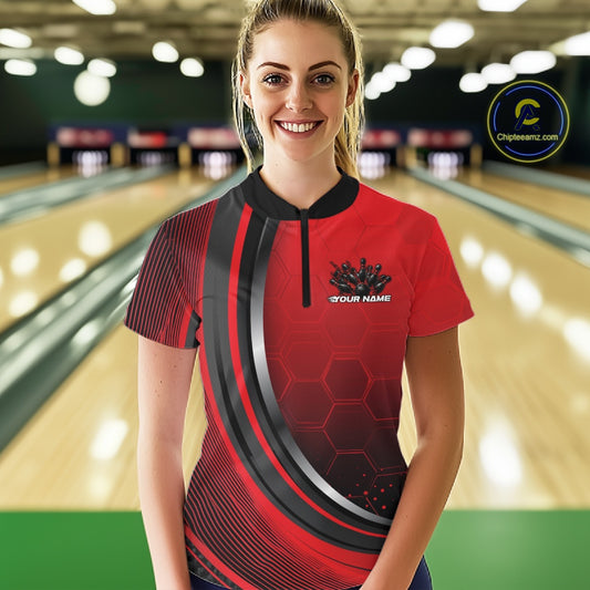 Female model wearing a black and red bowling quarter zip with honeycomb artwork and flaming bowling strike graphics at the bowling lane.