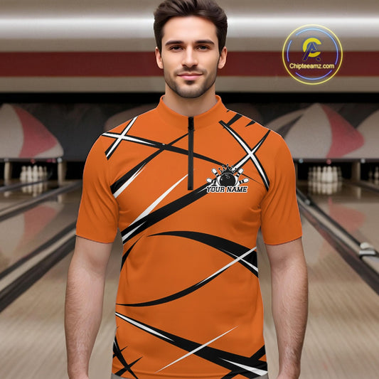 Front view of a male bowler wearing an orange, black, and white bowling quarter zip shirt in a bowling alley