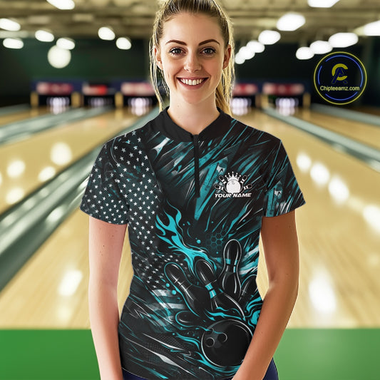 Female model in a bowling lane wearing black and turquoise blue quarter zip shirt, front view featuring patriotic flaming bowling ball hitting pins dynamic sports design