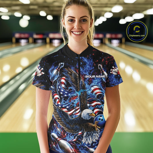 Female model front view in a bowling lane wearing a bowling quarter zip shirt with flaming eagle artwork, blue bowling ball, American flag, and blue flames.