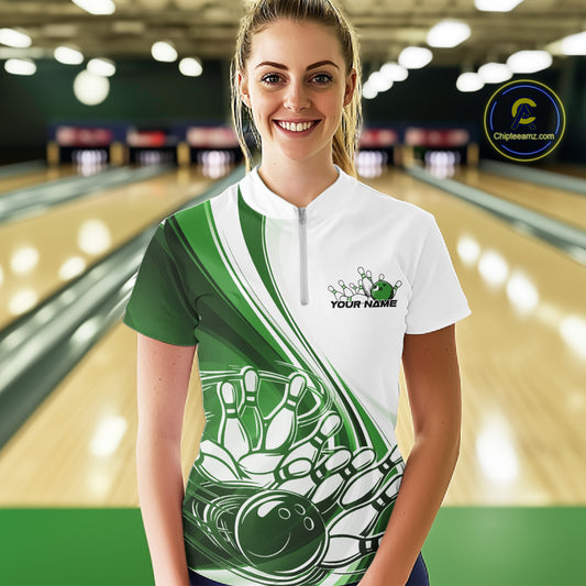 Front view of a female model in a white and green bowling quarter zip with flowing curve graphics and a bowling ball crashing into pins motif at the bowling lane.