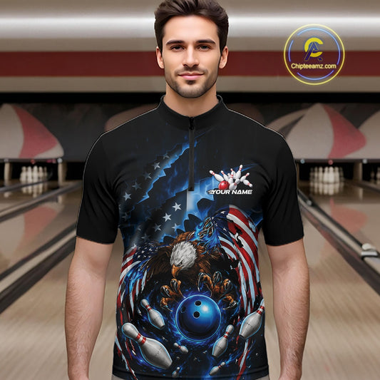 Male model front view at the bowling lane wearing a quarter zip shirt with a bald eagle gripping a blue bowling ball and flying pins.