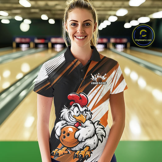 A woman stands in a bowling alley wearing a custom short-sleeve bowling polo shirt. The shirt features a black, white, and orange diagonal striped pattern with a cartoon graphic of a white chicken holding a bowling ball on the front.