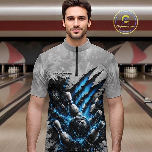 Front view of a male model wearing a gray bowling quarter zip shirt featuring a dramatic blue bowling ball and pins graphic with bold claw-mark artwork in a bowling lane.