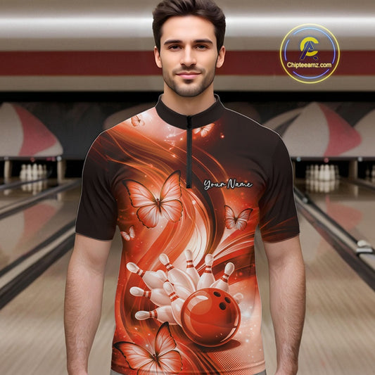 Male model at the bowling lane wearing an orange quarter-zip bowling shirt with bowling strike artwork and butterflies.