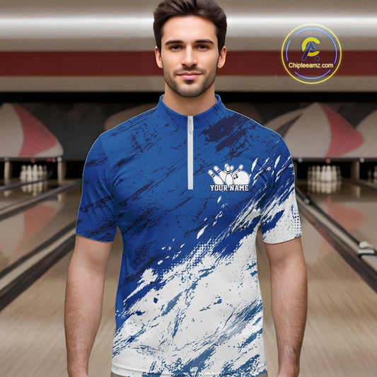 Front view of a male bowler wearing a white and blue bowling quarter-zip shirt with a splatter-inspired sports jersey design in a bowling lane