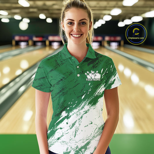 Woman wearing a green and white polo shirt with a logo in a bowling alley.