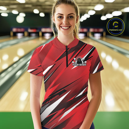 Woman wearing a red and black bowling shirt with a logo in a bowling alley.