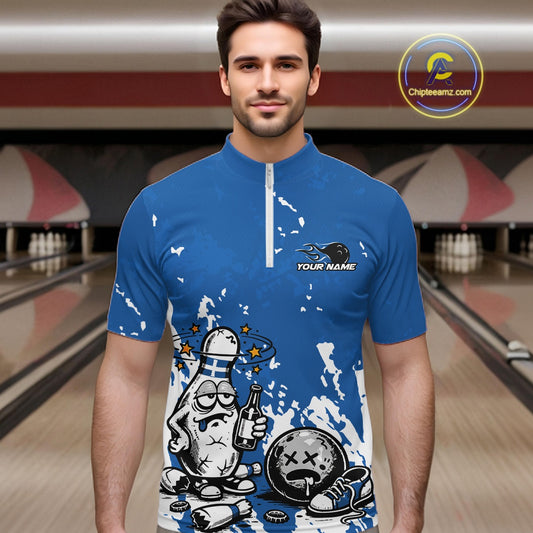 Male model in a bowling lane wearing a blue and white quarter-zip shirt, splatter graphic humorous bowling pin illustration holding beer and ball.