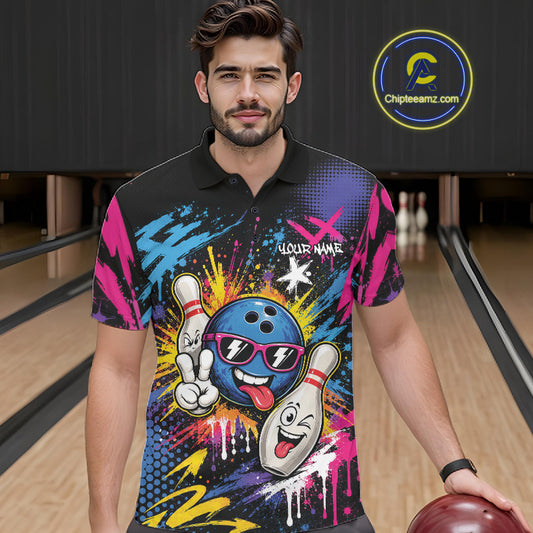 A man wearing a black short-sleeve bowling-themed graphic polo shirt with a colorful cartoon bowling ball and pin design, standing in a bowling alley holding a bowling ball.