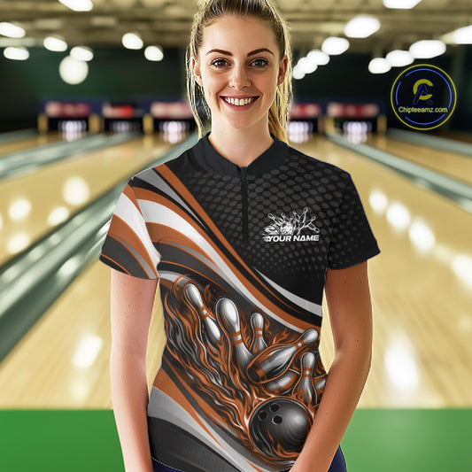 Front view female model wearing black and orange quarter zip bowling shirt in bowling lane, vibrant flame bowling ball and pins design