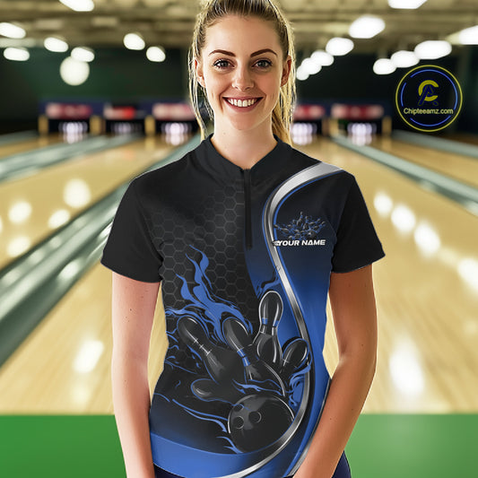 Female model front view inside bowling venue wearing black and blue quarter zip shirt with flaming bowling strike themed artwork