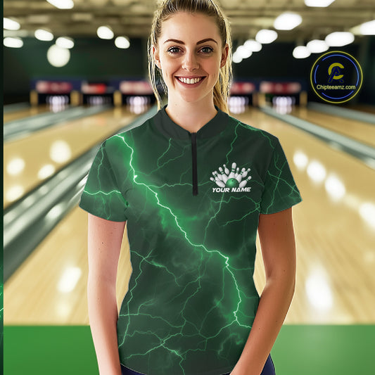 Female model wearing a bowling quarter-zip with green cobra, bowling ball, pins, and lightning accents in a bowling lane.