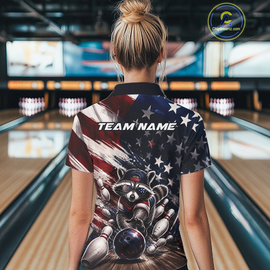 Back view of a female model at a bowling lane wearing a bowling polo shirt featuring a raccoon in patriotic sunglasses rolling a bowling ball through scattered pins with a distressed American flag backdrop.