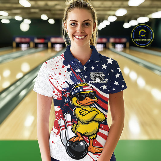 Front view of a female model in a bowling alley wearing a bowling polo with patriotic duck artwork and bowling ball accents.