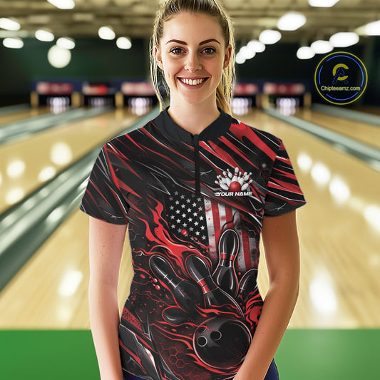 Female model in a bowling lane wearing black and red quarter zip shirt, front view showcasing patriotic flaming bowling ball hitting pins bold graphic design
