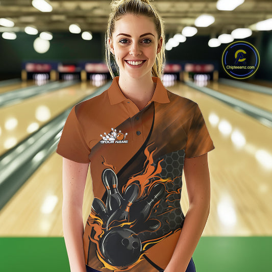 Female model wearing a black and orange bowling polo shirt at a bowling lane with fiery bowling action artwork and geometric accents.