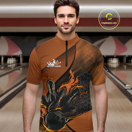 Male model wearing a black and orange bowling quarter-zip shirt at a bowling lane with fiery bowling action artwork and geometric accents.
