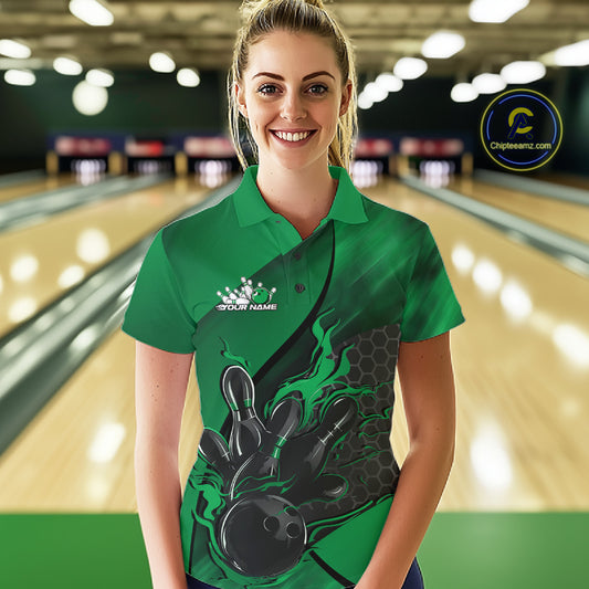 Female model at a bowling lane wearing a black and green bowling polo shirt with fiery bowling strike artwork and hexagonal graphics.