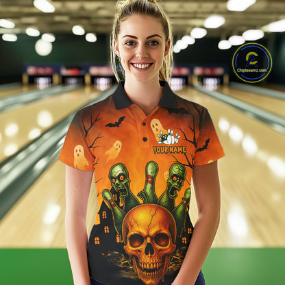 A woman stands in a bowling alley wearing a short-sleeve polo shirt with a Halloween-themed graphic print featuring a skull, green zombies, ghosts, and bats on an orange background. The shirt has a dark collar and the text 'YOUR NAME' on the chest.