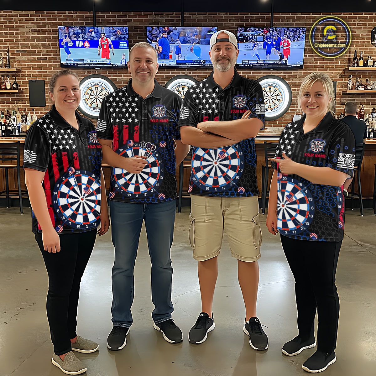Group of four people in a sports bar wearing matching custom black darts team polo shirts featuring an American flag and dartboard design.