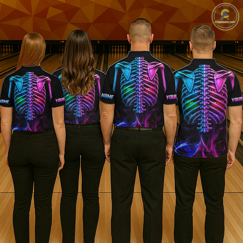 Four people standing in a bowling alley, viewed from behind, wearing matching black short-sleeve shirts with a vivid neon skeleton back print in blue, purple, pink, and green. The shirts have placeholder text on the back and the left sleeve, and the people are wearing black pants.