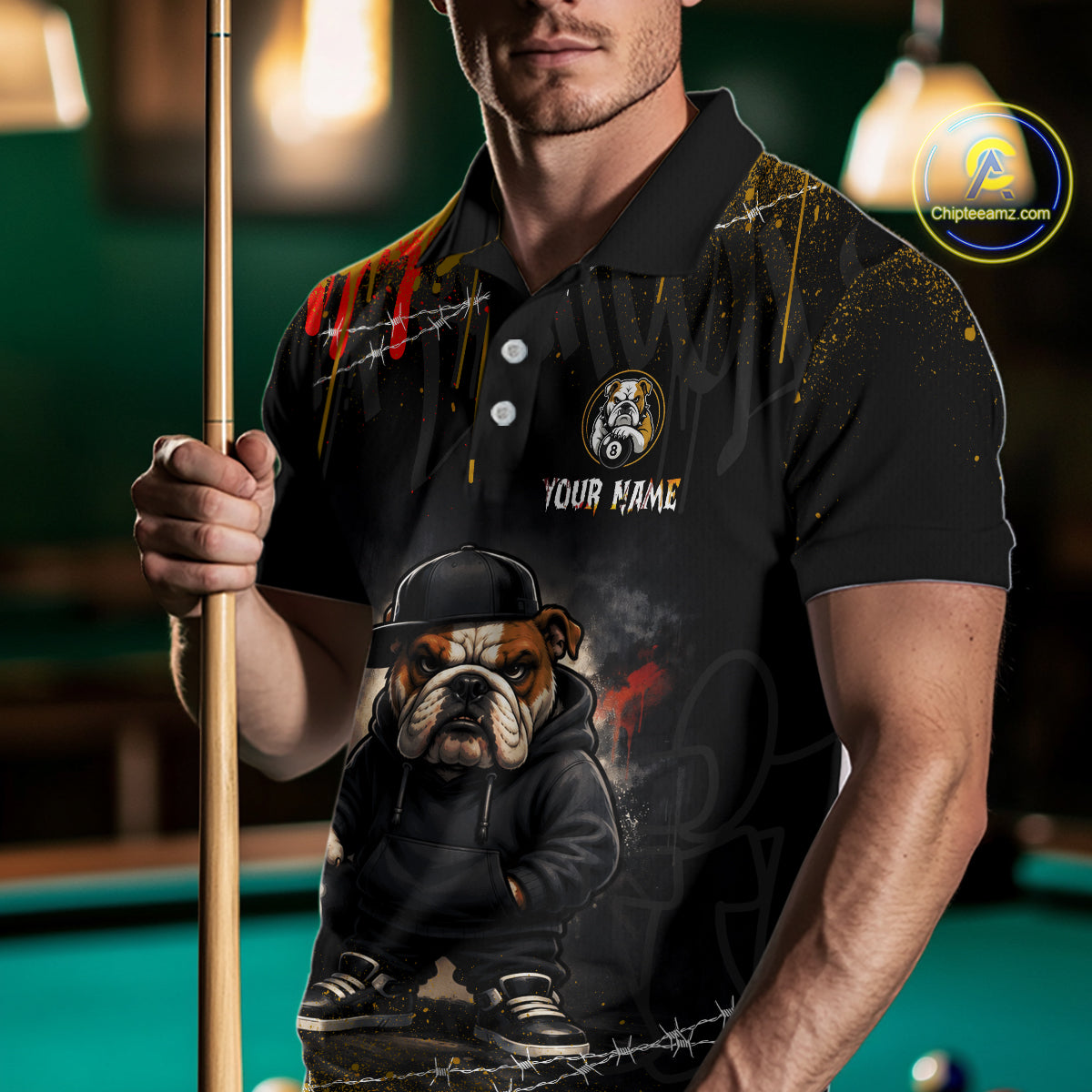 A front view of a custom street style billiards polo shirt worn by a male model holding a pool cue. The shirt features a funny hip hop bulldog and an 8-ball on the front. A 'YOUR NAME' text placeholder. The background is a blurred billiards room with a green pool table.