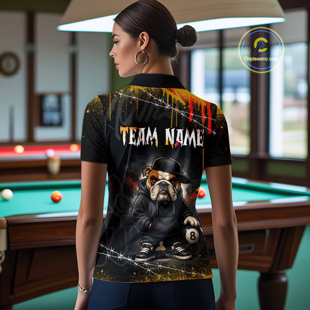 A back view of a custom black hip hop bulldog billiards polo shirt worn by a female model. The shirt features a bulldog on the back, with a large white 'TEAM NAME' text placeholder. The background is a billiards room with a table and hanging lights.