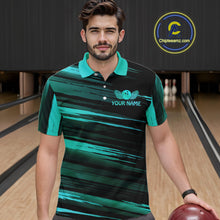 Load image into Gallery viewer, Male model wearing a custom black turquoise bowling polo shirt front view featuring a turquoise bowling ball emblem, dynamic turquoise brush stroke pattern and striped design at the bowling alley