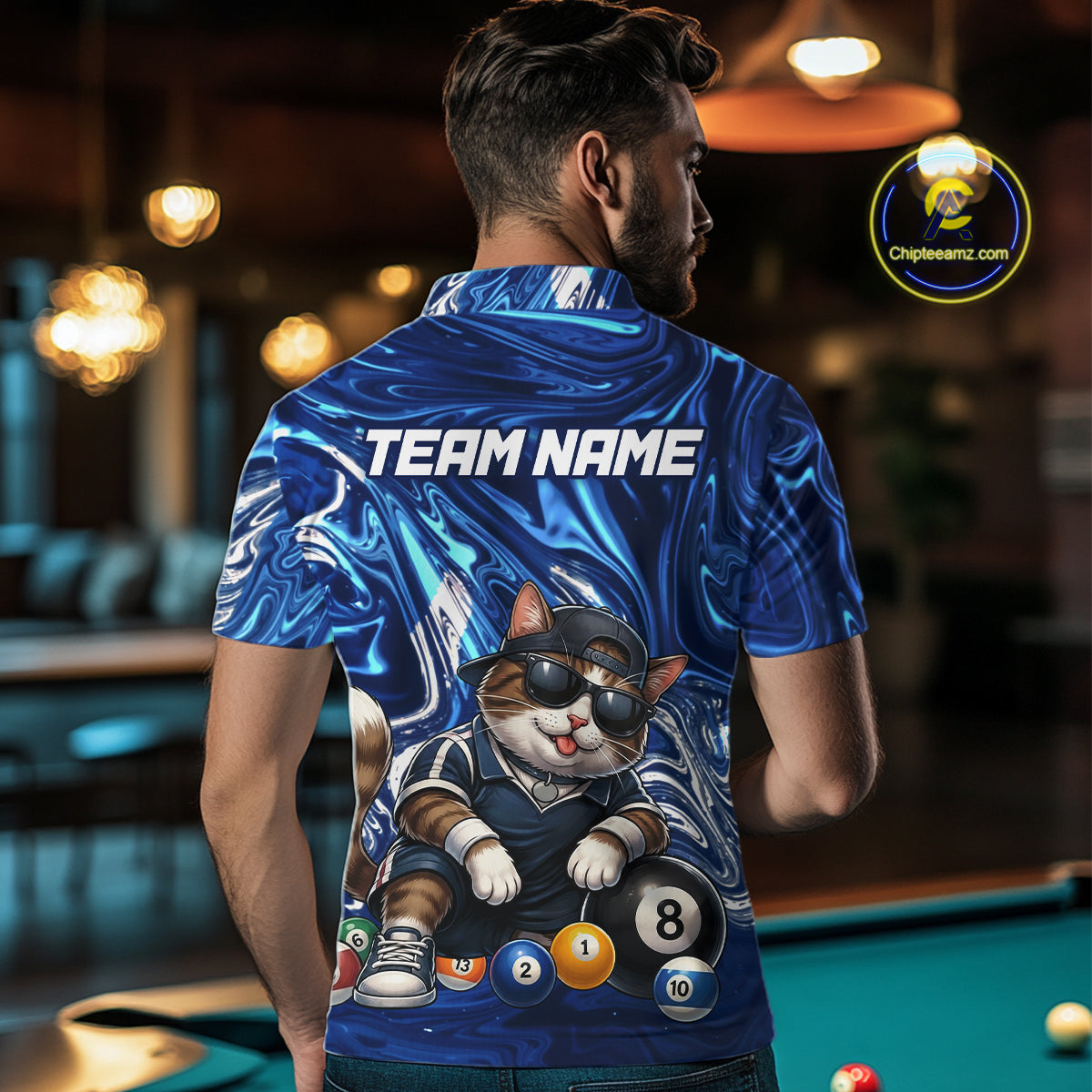 Person wearing a blue marbled billiard shirt with a cat design and 'Team Name' text, standing in a bar.