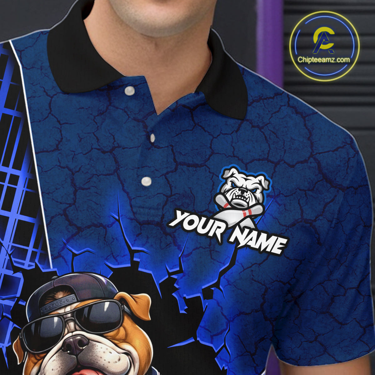 A close-up of a person wearing a blue short-sleeve polo shirt with a black collar. The shirt has a cracked blue graphic background, a bulldog mascot logo with the text 'YOUR NAME', and a large bulldog graphic in the lower left corner.
