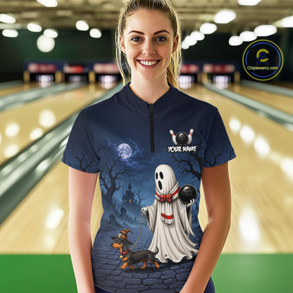 A woman wearing a dark navy blue bowling shirt with a Halloween graphic print featuring a ghost dog and a customizable name patch, set against a blurred bowling alley background.