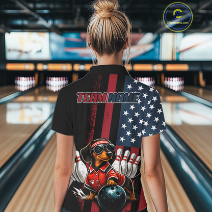 Person wearing a black bowling shirt with a dachshund graphic and 'TEAM NAME' text in a bowling alley.