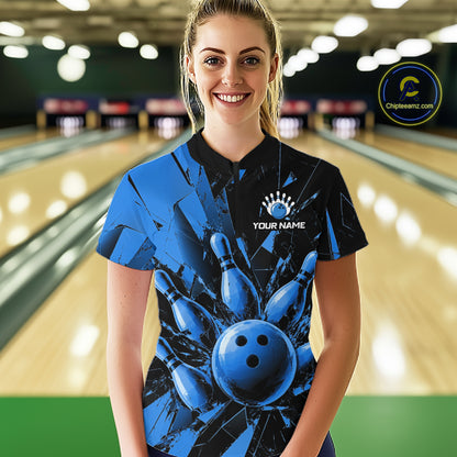 A woman stands in a bowling alley wearing a short-sleeve bowling shirt with a blue and black graphic design featuring bowling pins and a bowling ball, with a custom name printed on the chest. 
