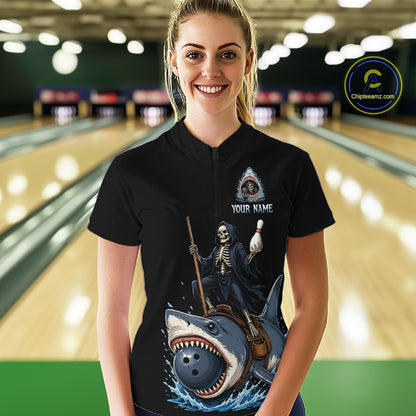 A woman stands in a bowling alley wearing a black short-sleeve polo shirt with a large graphic print of a grim reaper riding a shark. The shirt has a customizable design with a small eye logo and the text 'YOUR NAME'.