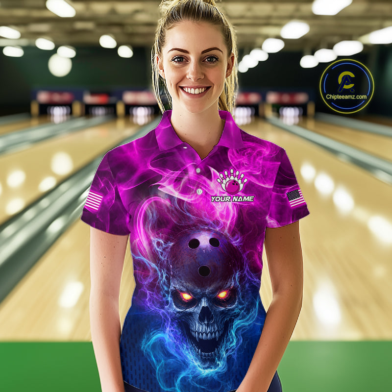 A woman standing in a bowling alley wearing a short-sleeve collared shirt with a vivid purple, pink, and blue skull graphic on the front. The shirt has a mock neck, short sleeves, and a small chest graphic that reads 'YOUR NAME'.