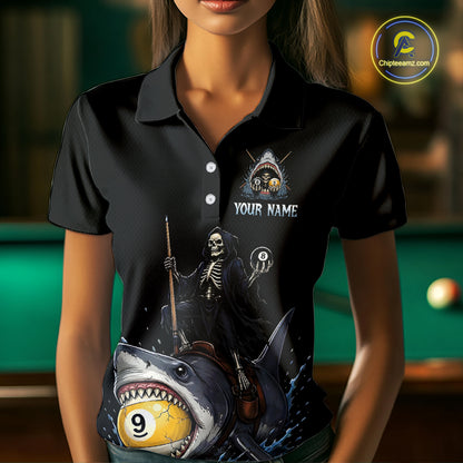 Black polo shirt with a graphic design of a skeleton riding a shark with a pool ball, worn by a person in front of a pool table.
