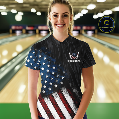 Woman wearing a black patriotic bowling quarter zip shirt featuring distressed American flag graphics, custom player name text, and a bald eagle with spread wings above a flag-themed bowling ball and pins.