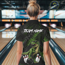 Load image into Gallery viewer, Women wearing bowling polo shirt featuring a dinosaur standing among bowling pins and ball artwork on black green textured background.