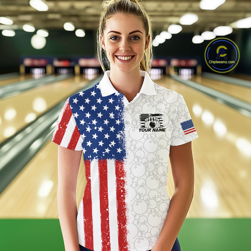 A woman stands in a bowling alley wearing a short-sleeve polo shirt with a split American flag design: one half shows a distressed red, white, and blue flag pattern, and the other half is white with bowling pin graphics and the text 'YOUR NAME'. 