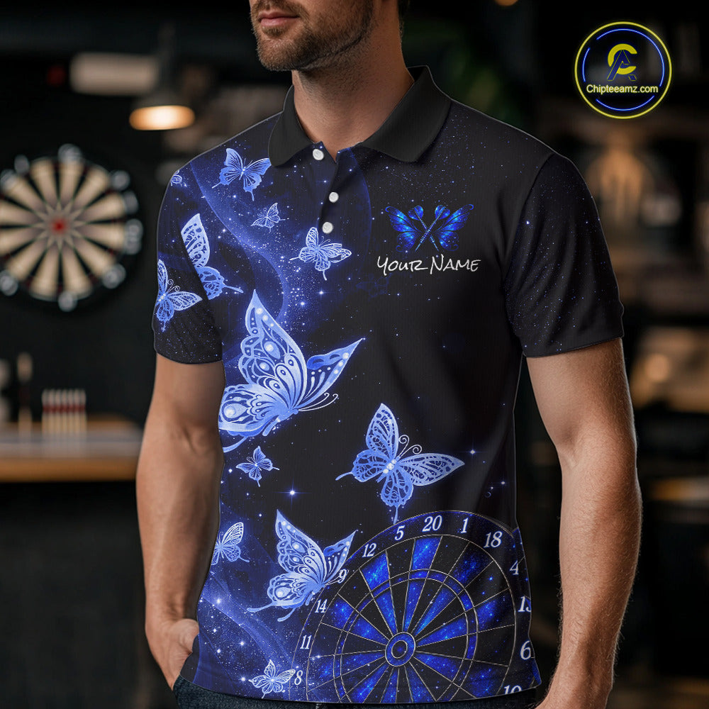 A man wearing a black short-sleeve polo shirt with a blue and white butterfly and dartboard graphic print, standing in a dimly lit indoor environment.