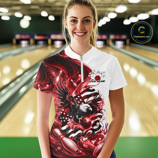 Female model front view at a bowling lane wearing a white and red quarter zip shirt with eagle graphics and flowing American flag inspired artwork.