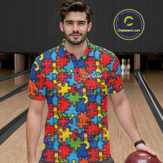 A man wearing a short-sleeve polo shirt with a colorful puzzle-piece pattern in red, blue, yellow, green, and purple, standing in a bowling alley. The shirt has 'YOUR NAME' printed on the chest
