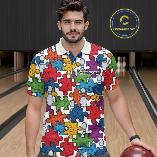 A man wearing a colorful short-sleeve polo shirt with a jigsaw puzzle pattern in red, blue, green, yellow, orange, and purple, standing in a bowling alley holding a bowling ball.