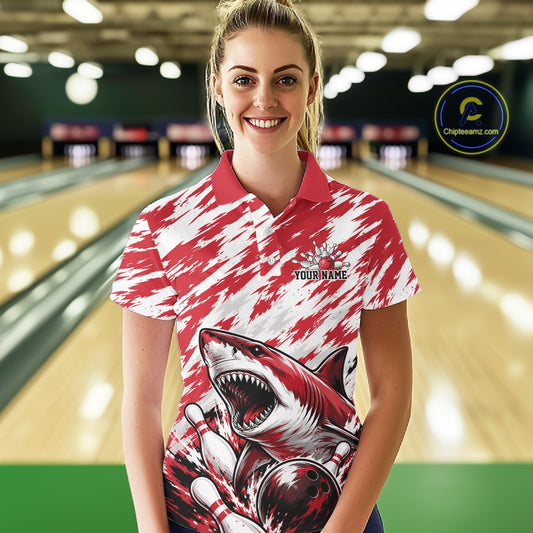 Woman wearing a red and white polo shirt with a shark design in a bowling alley.