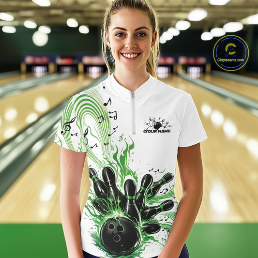 Female model wearing a white and green bowling quarter-zip shirt at the lane with bowling strike artwork and music-themed wave graphics.